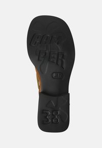 Suela de zapato de goma negra con detalles en relieve "CAMPER" y tamaño "38". Presenta una forma curva y una superficie texturizada para mayor agarre.