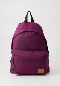 Lila szövet hátizsák fekete pántokkal, felső füllel, első cipzáras zsebbel és texturált logófolttal. Egyszerű kialakítás, puha tapintású anyagból.