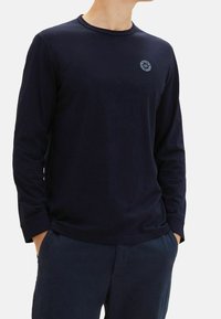 Marinen långärmad skjorta i mjukt material med rund hals; har en liten logotyp på bröstet och lätt ribbning vid ärmsluten.