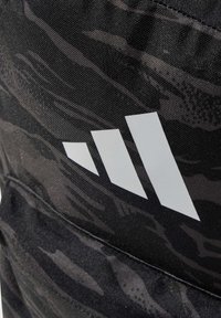 Mochila de camuflaje negra con un gran logo blanco de tres franjas. Fabricada con un tejido duradero con un acabado texturizado.