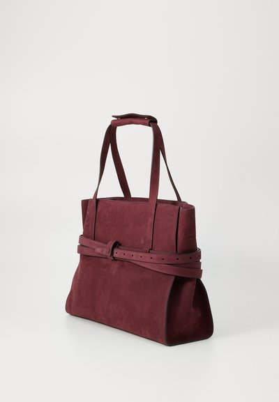 Τσάντα tote από σουέτ μπορντό με δύο μακριές λαβές, φαρδιά βάση και μια ζώνη γύρω από τη μέση, με ομαλή υφή.