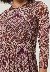 Robe multicolore présentant un motif complexe dans des tons de violet, marron et crème, avec des manches longues et une taille froncée.