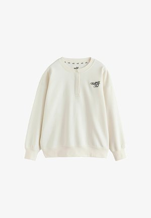 Cremefarbener Sweatshirt mit langen Ärmeln, geknöpftem Kragen, gerippten Bündchen und Saum sowie schwarzem "self. Wellness Club" Text auf der linken Brust.