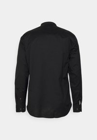 Camiseta negra de manga larga hecha de algodón, con cuello clásico y puños abotonados. Textura lisa sin patrones ni logotipos visibles.