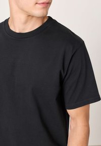 Schwarzes Baumwoll-T-Shirt mit Rundhalsausschnitt und kurzen Ärmeln, ausgestattet mit einer glatten Textur und einem normalen Schnitt.