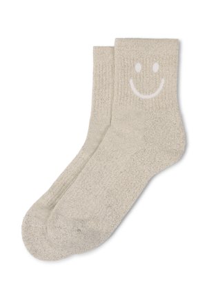 Jasnobeżowe bawełniane skarpetki z prążkowanymi ściągaczami i białą grafiką uśmiechniętej buzi na zewnętrznej stronie, z teksturowanym wykończeniem.