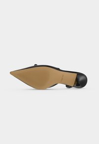Chaussure à talon haut noire à bout pointu, vue de la semelle avec un dessous beige texturé et la marque ALDO proche de la voûte plantaire.