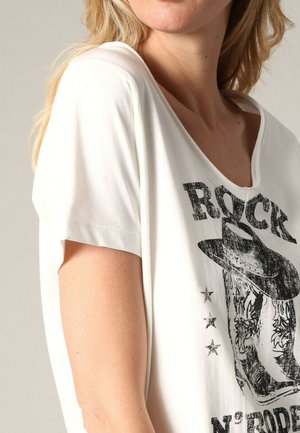 T-shirt blanc à manches courtes avec une coupe décontractée, ornée d'une impression noire d'un chapeau de cow-boy et du texte "ROCK N' RODEO", ainsi que des étoiles en accents.