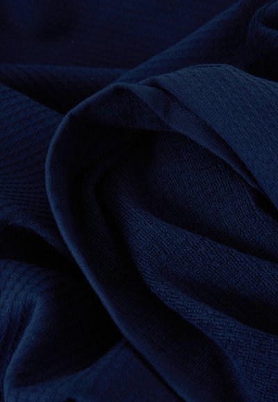 Σκούρο μπλε ύφασμα με απαλή, υφή επιφάνεια, διατεταγμένο σε απαλές πτυχώσεις και καμπύλες.