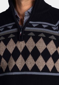 Gebreide trui met hoge kraag en halve rits. Heeft een geometrisch diamantpatroon in beige, zwart en grijs, met een gestructureerde stof.