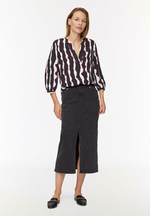 Blouse à rayures noir et blanc avec des accents roses, présentant un décolleté en V et des manches bouffantes ; associée à une jupe en denim foncé avec une fente devant.