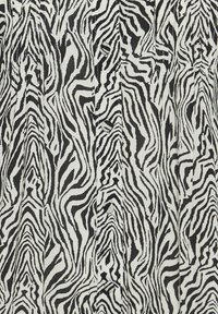 Tessuto a stampa zebra in bianco e nero con superficie testurizzata, caratterizzato da linee ondulate e piccoli bottoni lungo un lato.