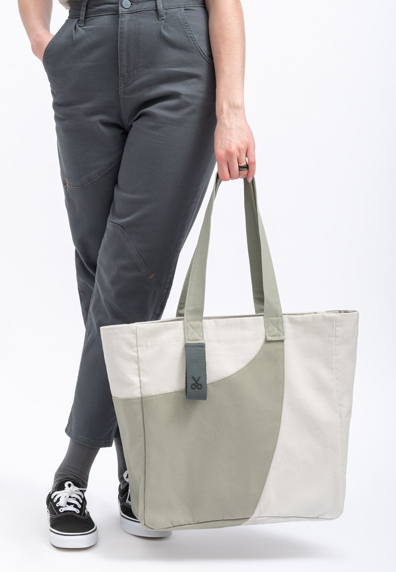 Borsa tote in tela beige e verde salvia con una texture liscia, caratterizzata da un design bicolore e da un manico cucito.