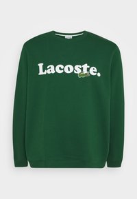 Felpa verde con logo bianco "Lacoste" e emblema di coccodrillo, realizzata in tessuto morbido, con scollo rotondo e polsini a costine.
