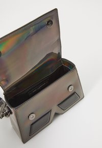 Holographic handbag with a structured design, featuring black accents, a snap closure, and an interior pocket with fabric lining.