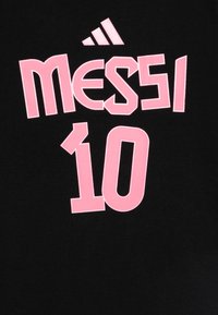 Svart t-skjorte med stor rosa tekst som viser "MESSI" over nummer "10," med en liten hvit Adidas-logo øverst.