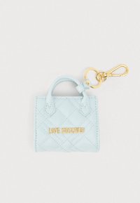 Μικρή τσάντα χειρός από ανοιχτό μπλε ψεύτικο δέρμα με ραφές, με μεταλλικά στοιχεία σε χρυσό τόνο, διαθέτει χειρολαβή στην κορυφή και τυπωμένο λογότυπο στο μπροστινό μέρος.