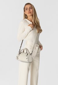 Piccola borsa a tracolla strutturata in pelle grigia chiara con manici arrotondati e tracolla rimovibile. Presenta dettagli in metallo.