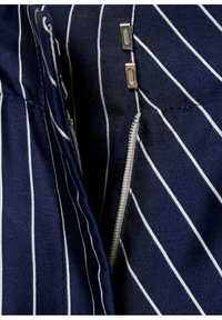 Tessuto blu navy con strisce verticali bianche, dotato di una cerniera laterale con due linguette metalliche e dettagli di cucitura visibili.
