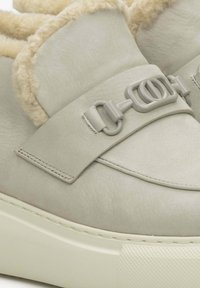 Lichtgrijze sneakerboot met een zachte beige voering, leren bovenwerk, brede band met grijze gespsluiting, en een dikke witte zool.