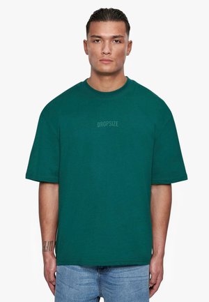 Türkises Baumwoll-T-Shirt mit Rundhalsausschnitt und kurzen Ärmeln. Verfügt über ein dezentes "DROPSIZE"-Logo auf der Brust. Lockerer Schnitt.