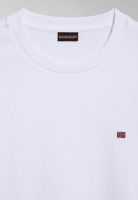 Hvid bomulds-sweatshirt med rund halsudskæring og et lille rødt og blåt broderet logo på venstre bryst. Blød tekstur, enkelt design.