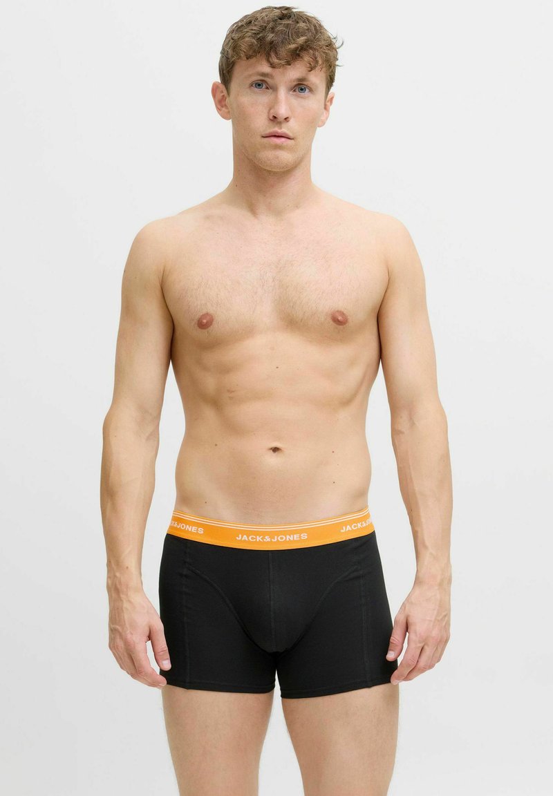 Melnas bokseru apakšbikses ar oranžu jostu, kurā ir rakstīts 'JACK & JONES'. Audums izskatās gluds un pieguļošs, uzsverot formas. 