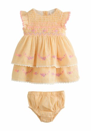 Žlté a biele pruhované detské šaty s ružovou kvetinovou výšivkou a volánovými rukávmi, doplnené o zladené nohavičky.