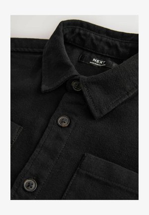 Puha anyagból készült fekete ing, gombos gallérral, elöl két zsebbel és barna műanyag gombokkal. A címke olvashatóan "NEXT".