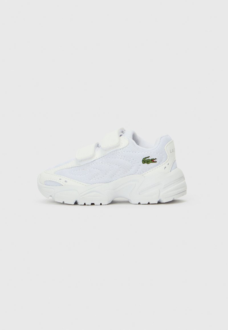 Scarpe da ginnastica bianche con una tomaia in rete, due cinturini in Velcro regolabili e una suola texture. Presenta un piccolo logo verde.