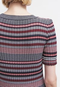 Stickad klänning med ribbat mönster och horisontella ränder i röd, marinblå och vit. Korta ärmar och rundad krage.