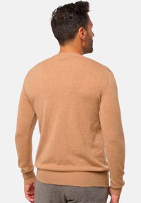 Beiger Rundhalsausschnitt-Pullover aus weichem Material, mit gerippten Bündchen und Saum. Er verfügt über eine glatte Textur und eine figurbetonte Silhouette.