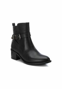 Bota de tobillo de cuero negro con punta redondeada, tacón de bloque y detalle de correa con hebilla en el lateral; textura suave y líneas limpias.