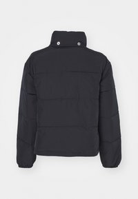 Svart puffjacka med hög krage, långa ärmar och sydda horisontella paneler. Har tryckknappar vid kragen och elastiska manschetter.