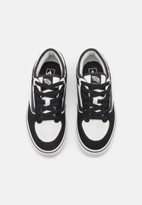 Zapatillas en blanco y negro con parte superior de ante y lona, punta redonda, cordones planos y suela de goma con entresuela blanca.