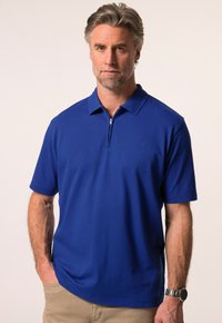 Královsky modré polo tričko s kr átkým rukávem, zipovým výstřihem a texturovanou látkou. Obsahuje minimální branding na hrudi.