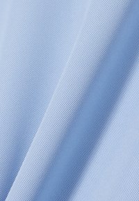 Vaaleansininen teksturoitu kangas, jossa on verkkomainen kuvio, pehmeä koostumus ja laskeutuva ulkonäkö, korostaen syvyyttä ja kolmiulotteisuutta.