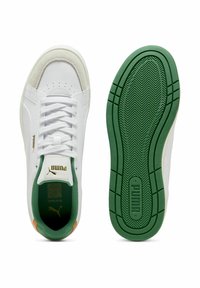 Zapatillas blancas con acentos de ante y suelas verdes. Cuentan con una suela de goma texturizada, cordones planos y un logo dorado cerca de la lengüeta.