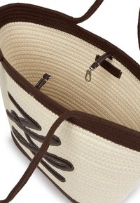 Austs, pītās krēmveida iepirkumu somas ar tumši brūnām akcentiem. Iekļauj rāvējslēdzēju, iekšējo kabatu un garas plecu siksnas.