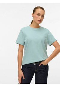 Lyseblågrøn, kortærmet t-shirt i blødt stof. Rund halsudskæring og afslappet pasform, kombineret med mørk denimjeans og et sort bælte.