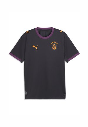 Maglia sportiva grigio scuro con colletto viola e bordi delle maniche, loghi Puma arancioni e stemma della squadra Galatasaray arancione con cinque stelle.