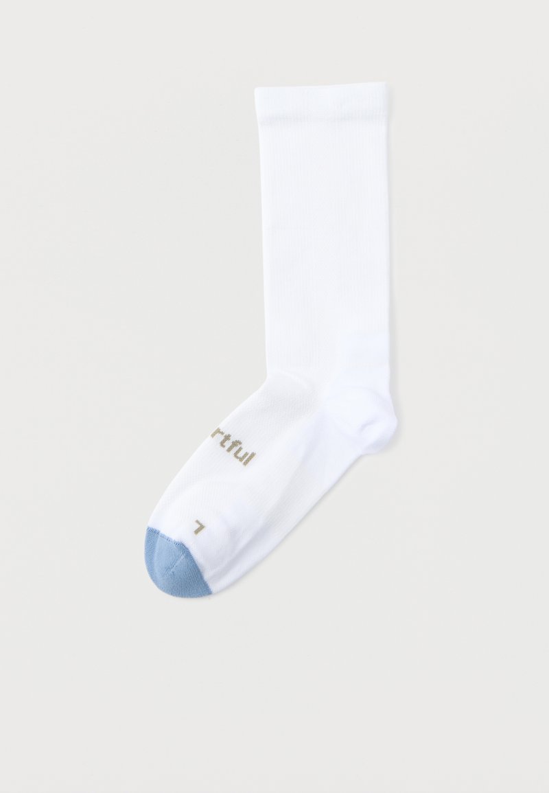 Chaussette blanche à bord-côte avec un bout bleu clair et un texte doré près du bout sur un fond gris clair.