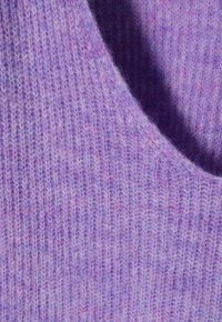 Lila gestrickter Stoff mit gerippter Textur, der subtile Variationen in Farbe und Weichheit aufweist. Glatte Oberfläche mit leichtem Gefühl.