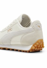 Puma Easy Rider sneakers van off-white leer, met een suède zijstreep, gouden branding en een rubberen buitenzool met opvallende nopjes.