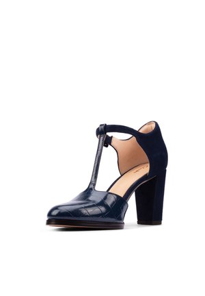 Marineblaue High-Heel-Schuhe mit T-Riemen, geschlossenem rundem Zeh, strukturiertem Leder vorne und Wildledermaterial an Ferse und Knöchelriemen.