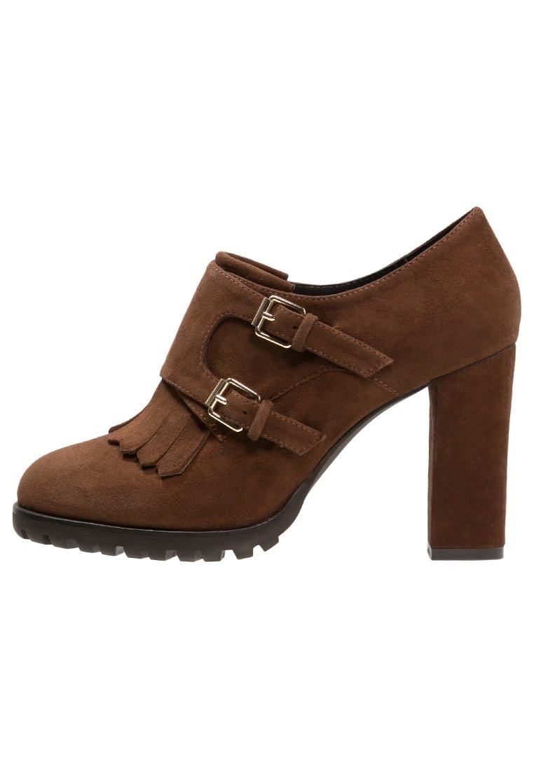 Scarpe con tacco alto in suede marrone, con due fibbie regolabili, dettagli frangianti nella parte anteriore e una suola spessa e testurizzata.