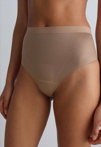 High-waisted beige underwear featuring a smooth, sheer fabric with a geometric texture and a wide, elastic waistband for comfort.