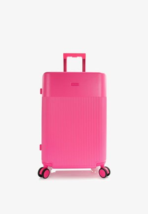 Valigia rigida rosa acceso con metà inferiore costolata, manico telescopico esteso e quattro ruote doppie girevoli.