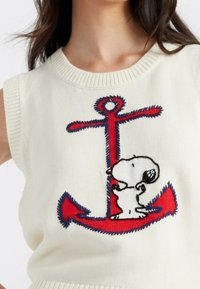 Weißer ärmelloser Pullover mit einem rot-blauen gestickten Ankerdesign und einem Cartoon-Hund. Strickstoff mit Struktur.