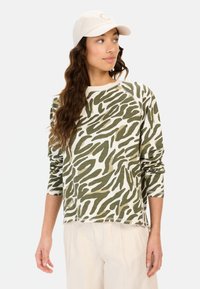 Grøn og creme langærmet skjorte med et bølget camouflage-mønster, blødt materiale og en rund halsudskæring. Matchende med lyse bukser.